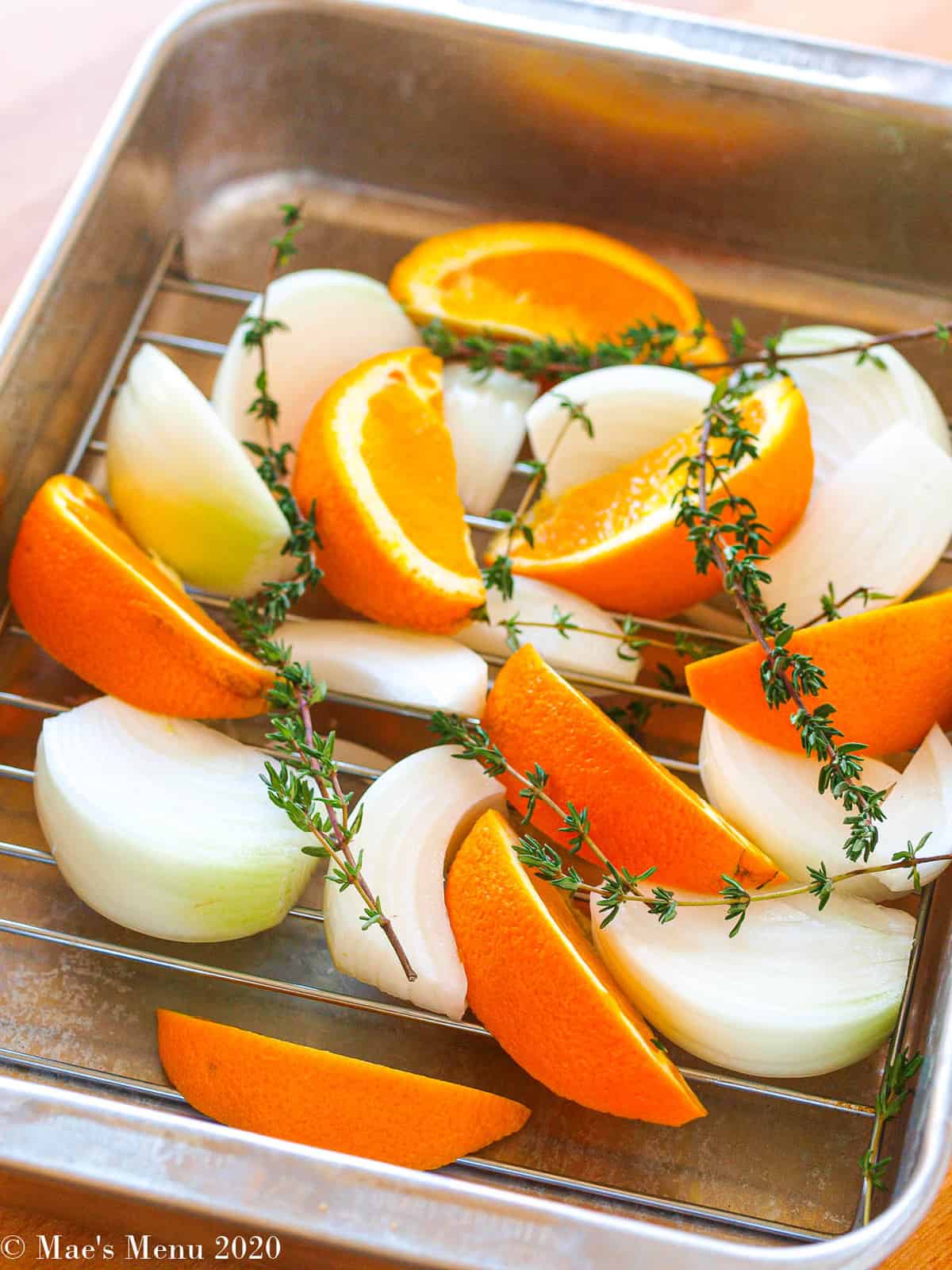 Orange wedges and onions on a roasting rack in a baking pan