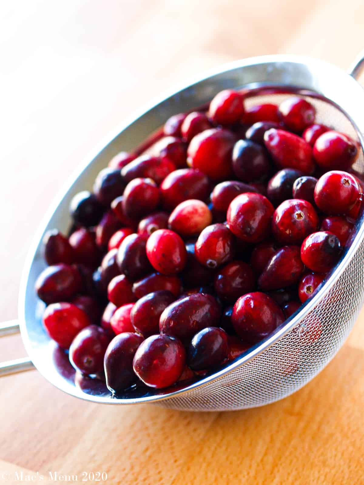 A wire mesh strainer full of washed cranberries