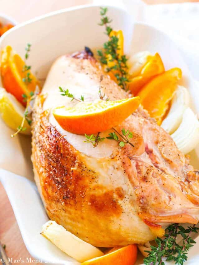 A white serving dish with roasted turkey breast in it.