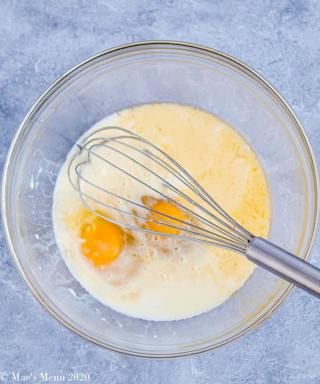 Milk, eggs, and butter in a large glass mixing bowl with a melt whisk