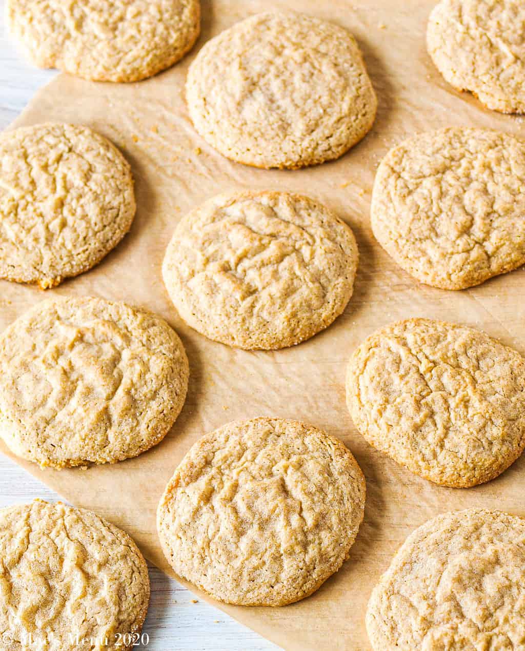 Peanut butter cookies spread out over a large piece of pachment paper