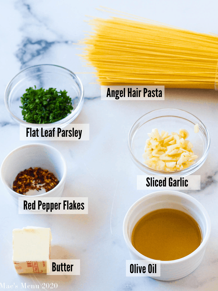 All the ingredients for garlic angel hair pasta, angel hair, olive oil, garlic, red pepper flakes, butter, and flat leaf parsley