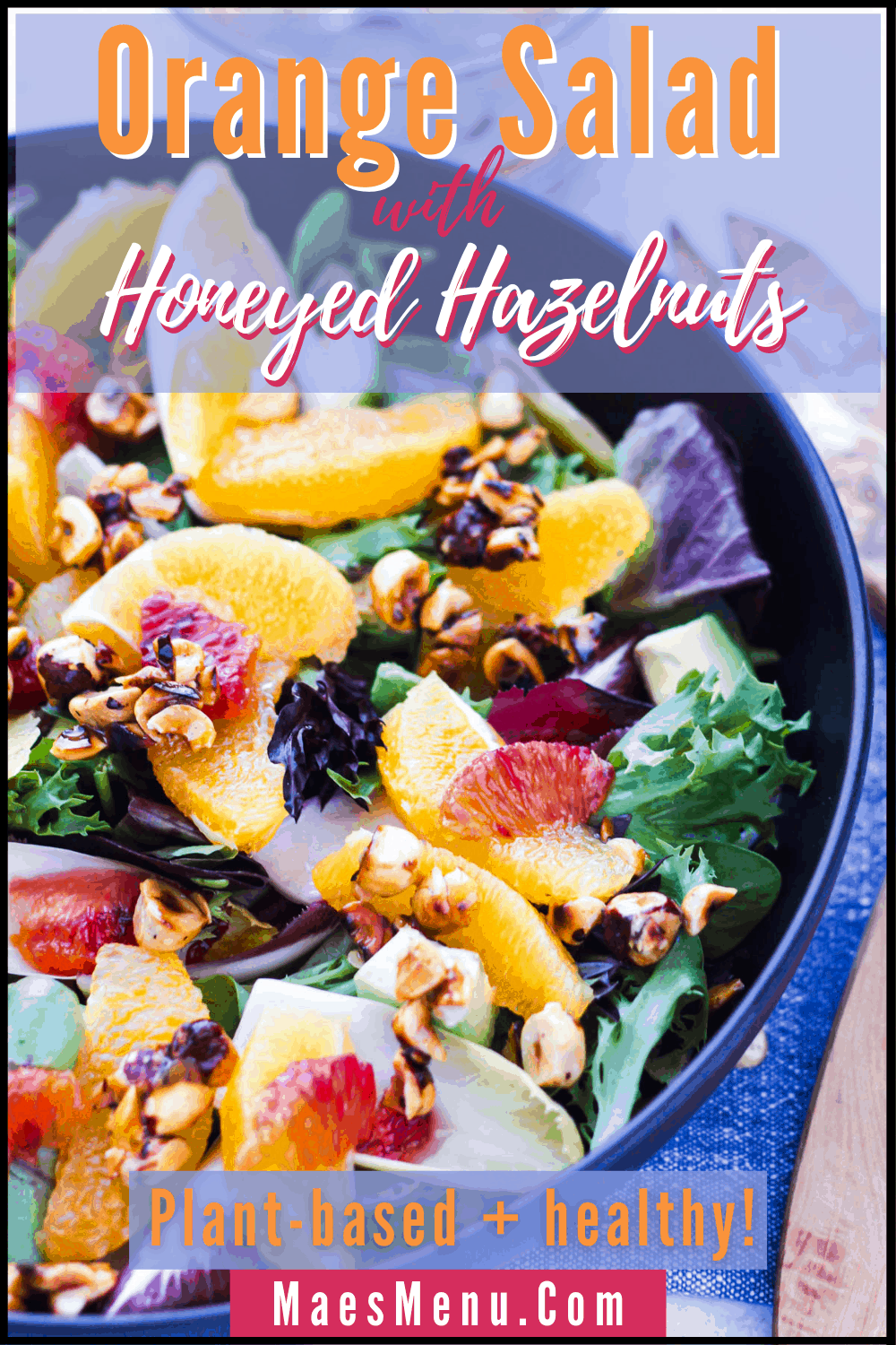 A pinterest pin for orange salad with honeyed hazelnuts. On the image is an angled overhead image of the salad in a black bowl