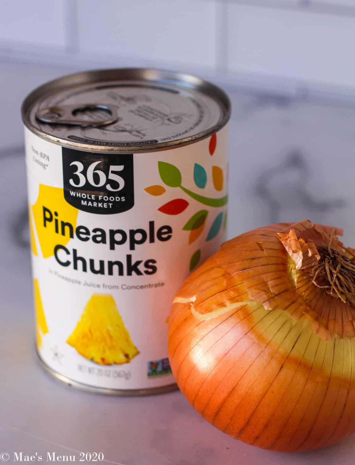 a large can of pineapple chunks next to a large sweet onion