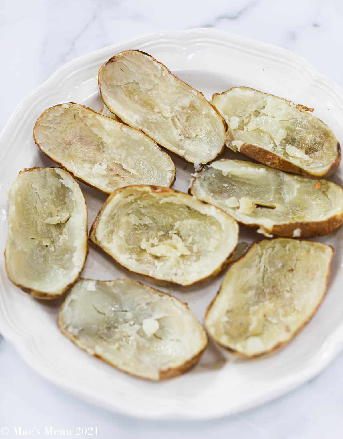 Russet potatoes sliced in half with the pulp scooped out 