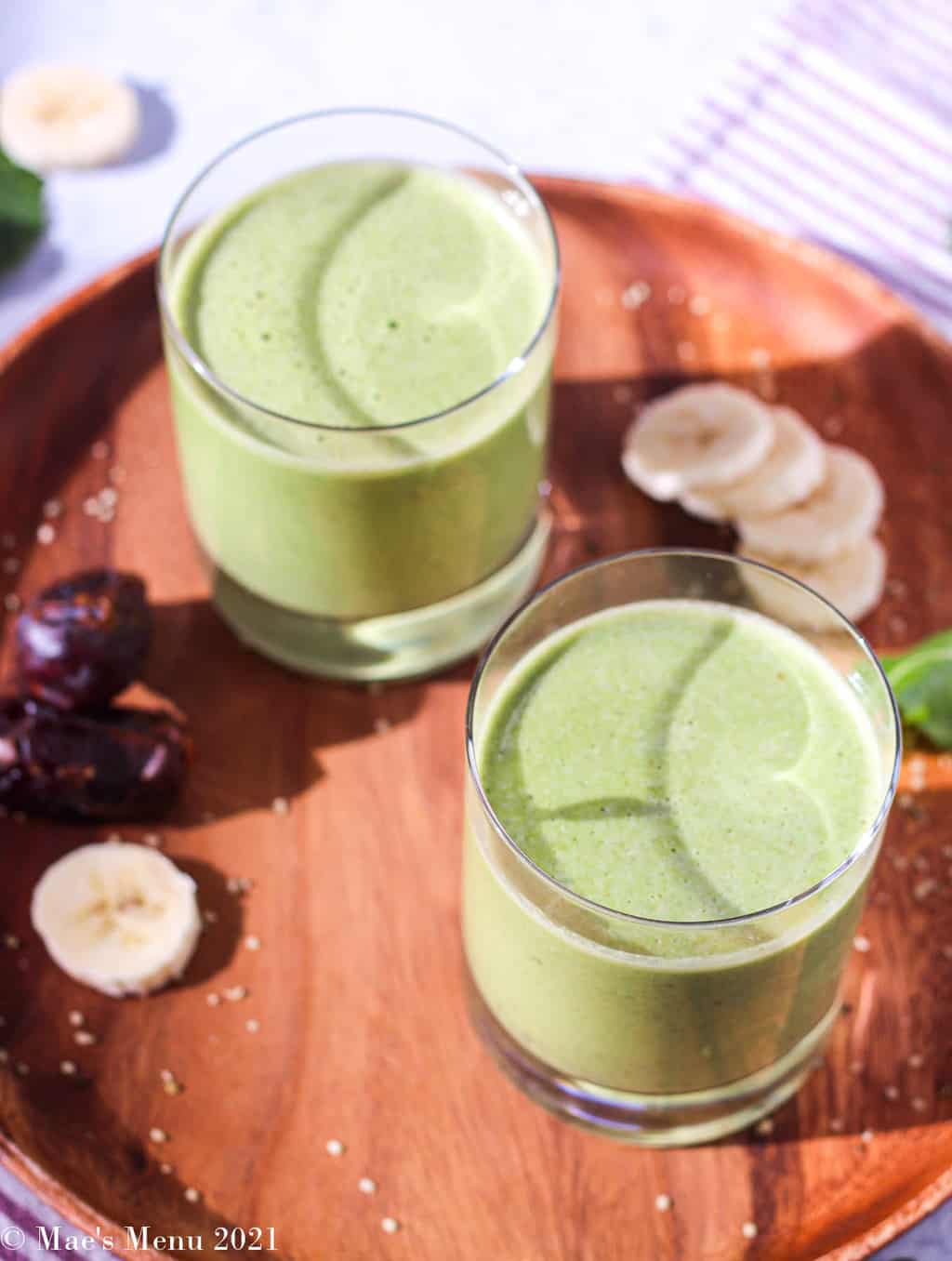 An overhead angled shot of two glasses of green peanut butter date smoothies
