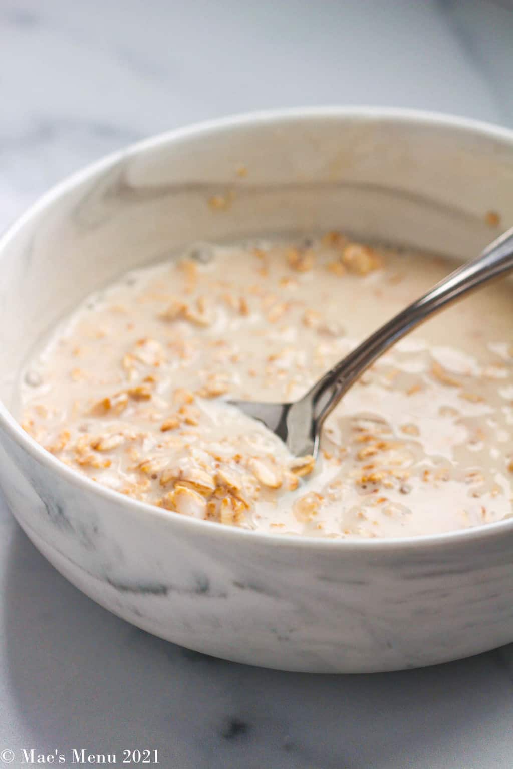 An up-close shot of a bowl of overnight oats with a spoon in it
