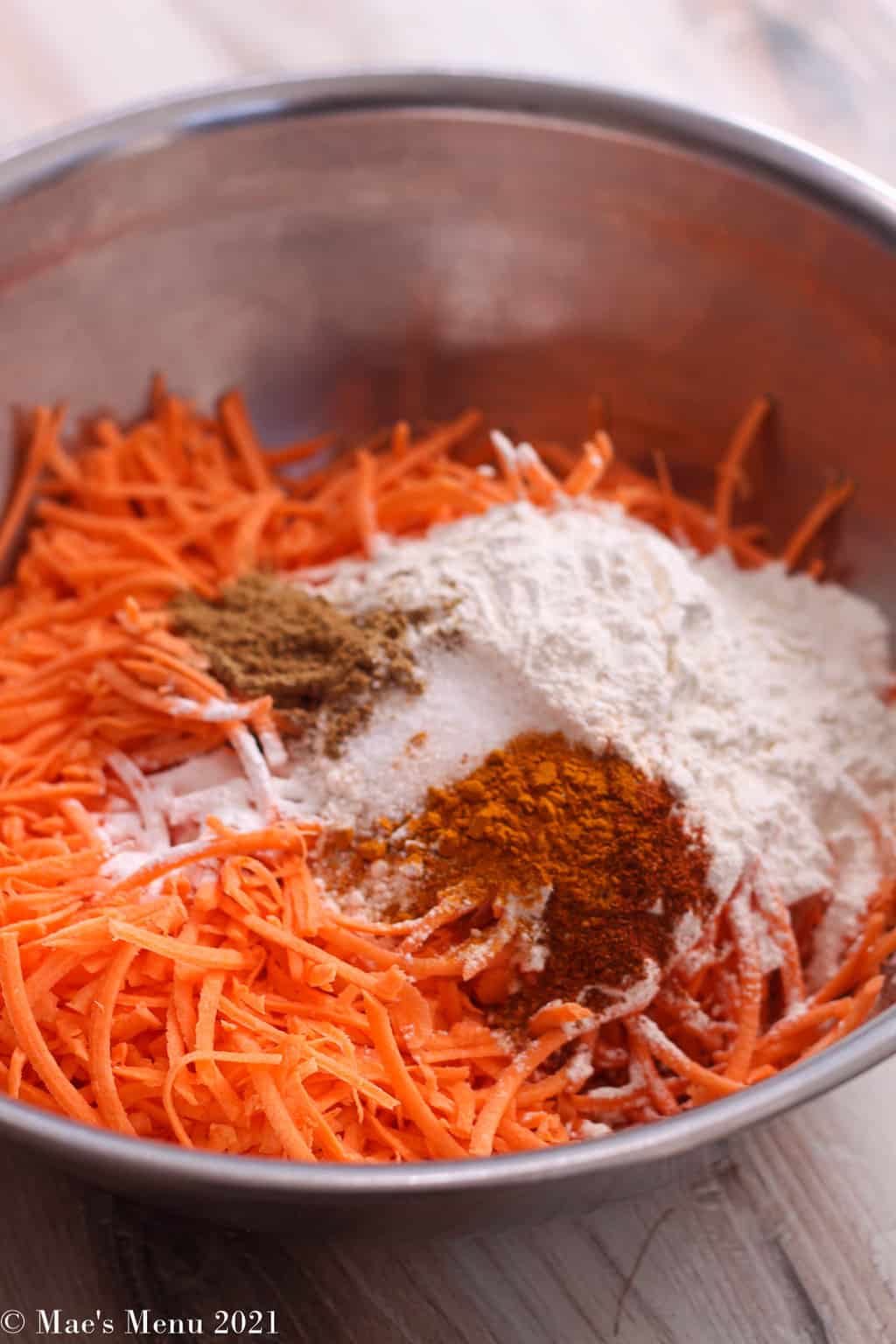 A large mixing bowl of shredded sweet potatoes, spices, and flour