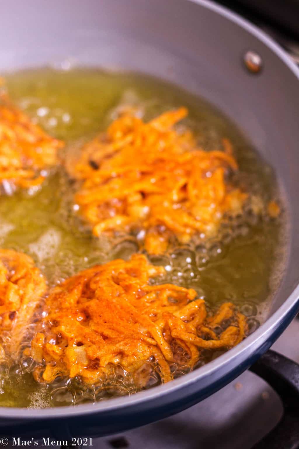 Sweet potato fritters frying in a large non-stick pan