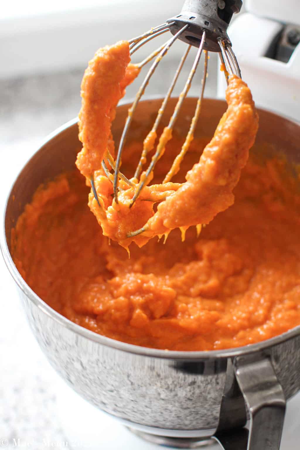 The sweet potato souffle in the stand mixer with the orange batter on the whisk