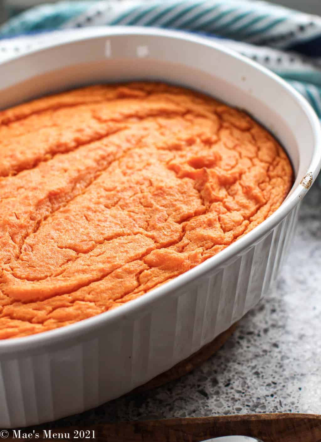 A side angle shot of a casserole dish full of sweet potato soufle on a granite counter
