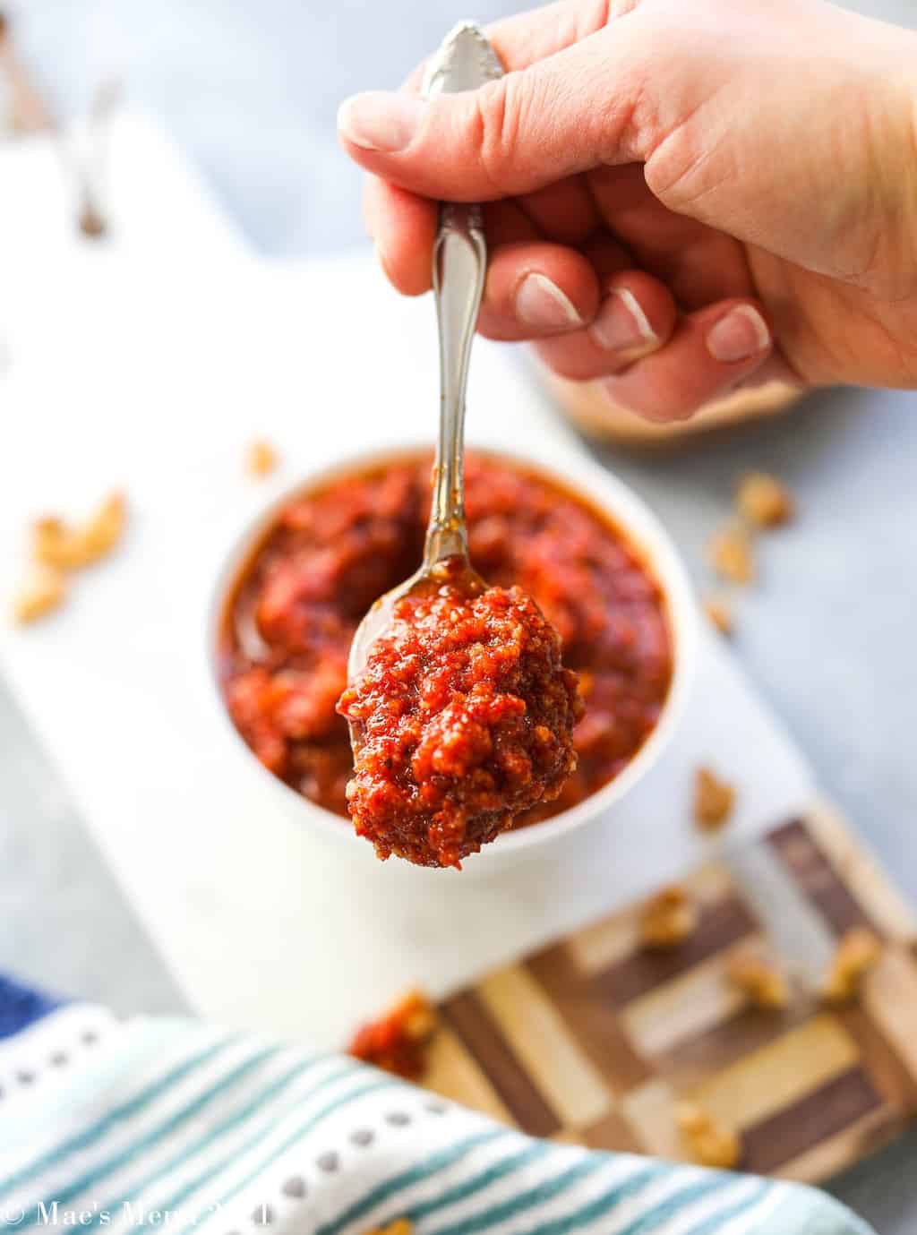 An up-close shot of a scoop of red pesto in front of the dish of pesto