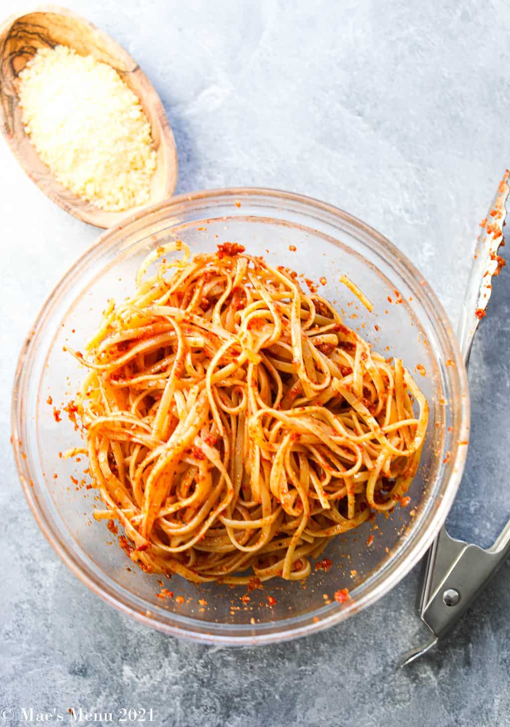 Pasta tossed with red pesto in a class mixing bowl
