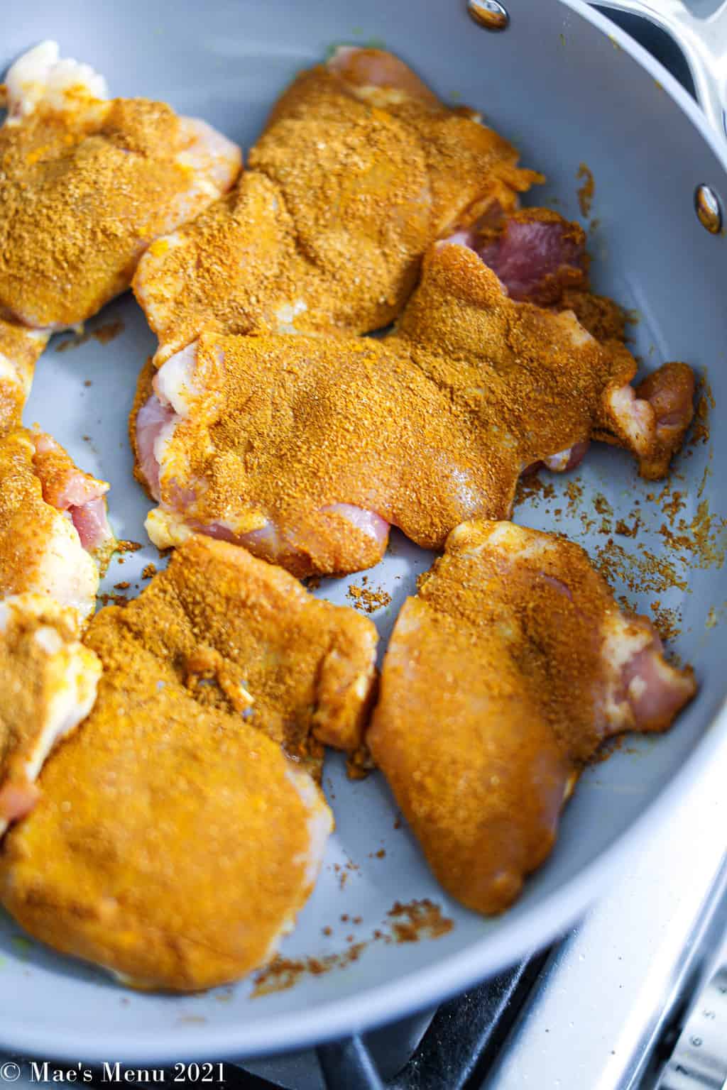 An up-close shot of turmeric rubbed chicken in a non-stick pan