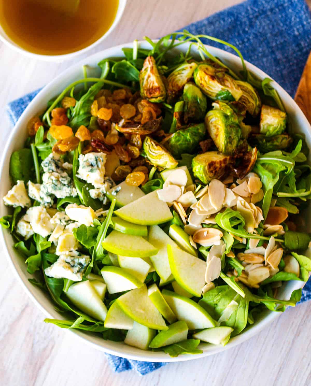 An overhead shot of a large bowl of brussels sprouts and arugula salad