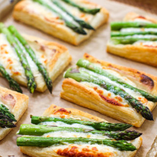 An elevated angle shot of a tray of cheesy asparagus tarts
