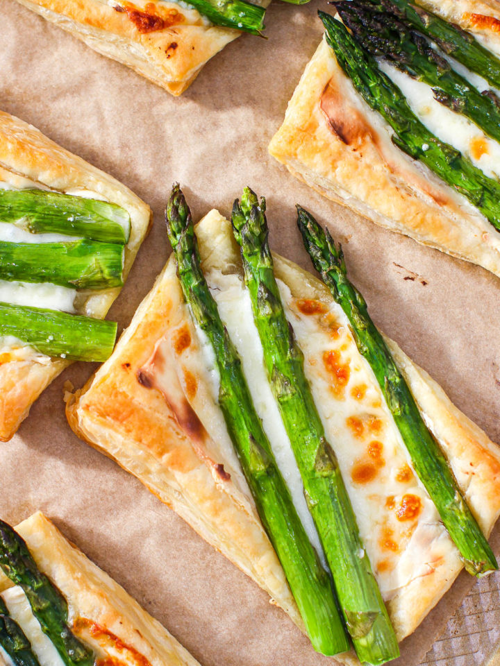 an overhead shot of cheesy asparagus tarts on a baking sheet