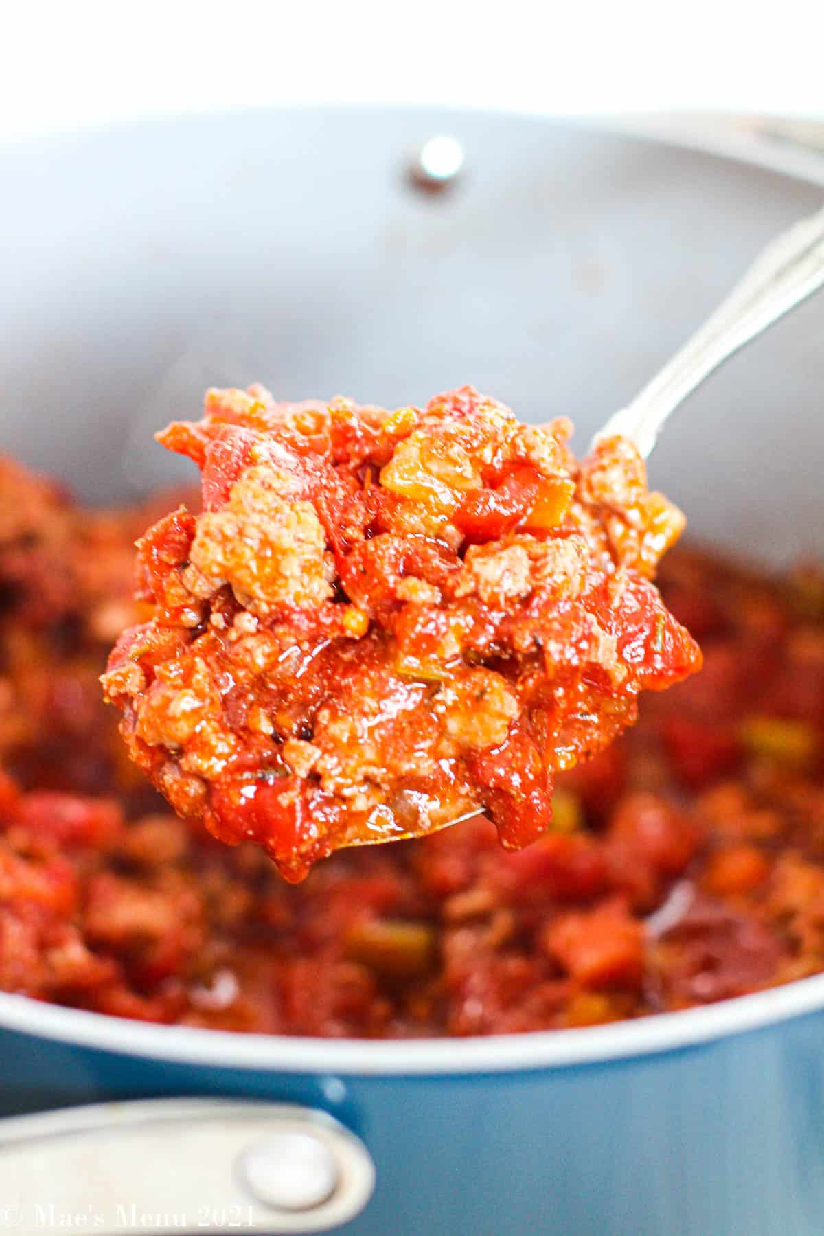 A large scoop of chicken bolognese sauce over a pot of the sauce