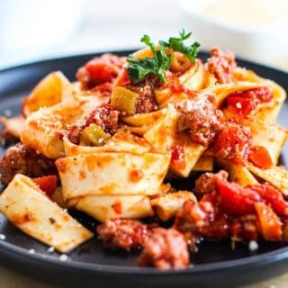 An up-close shot of chicken bolognese with a bowl of the sauce in the background