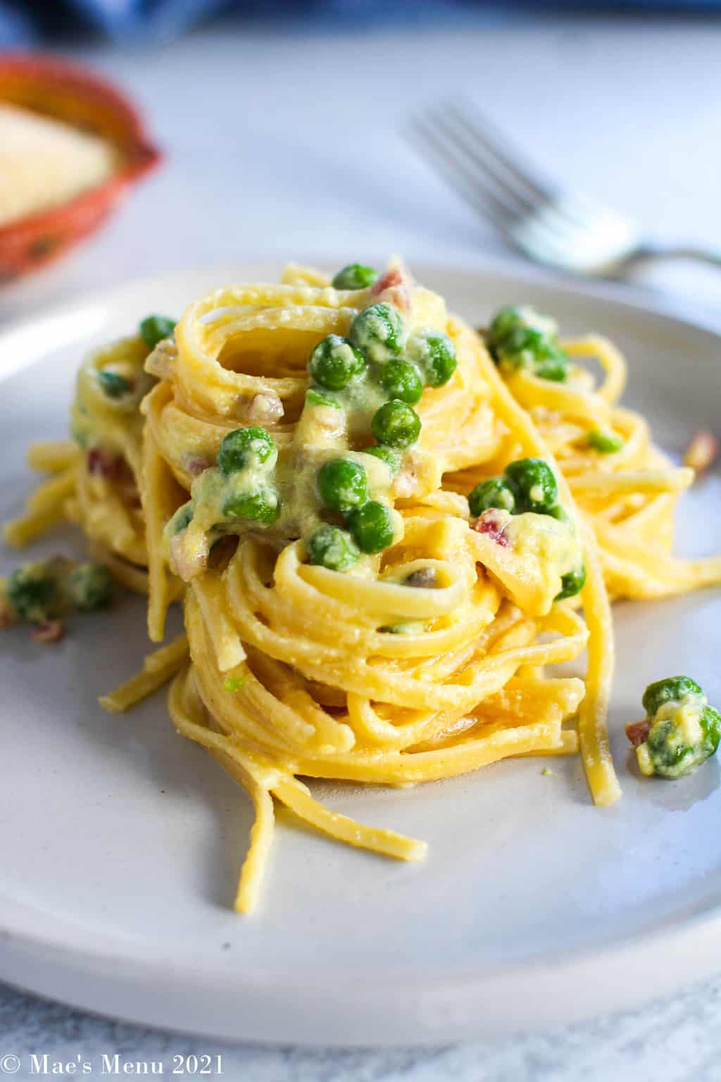 A up-close side shot of Creamy Lemon Ricotta Pasta with Peas on a white plate with a fork in the background