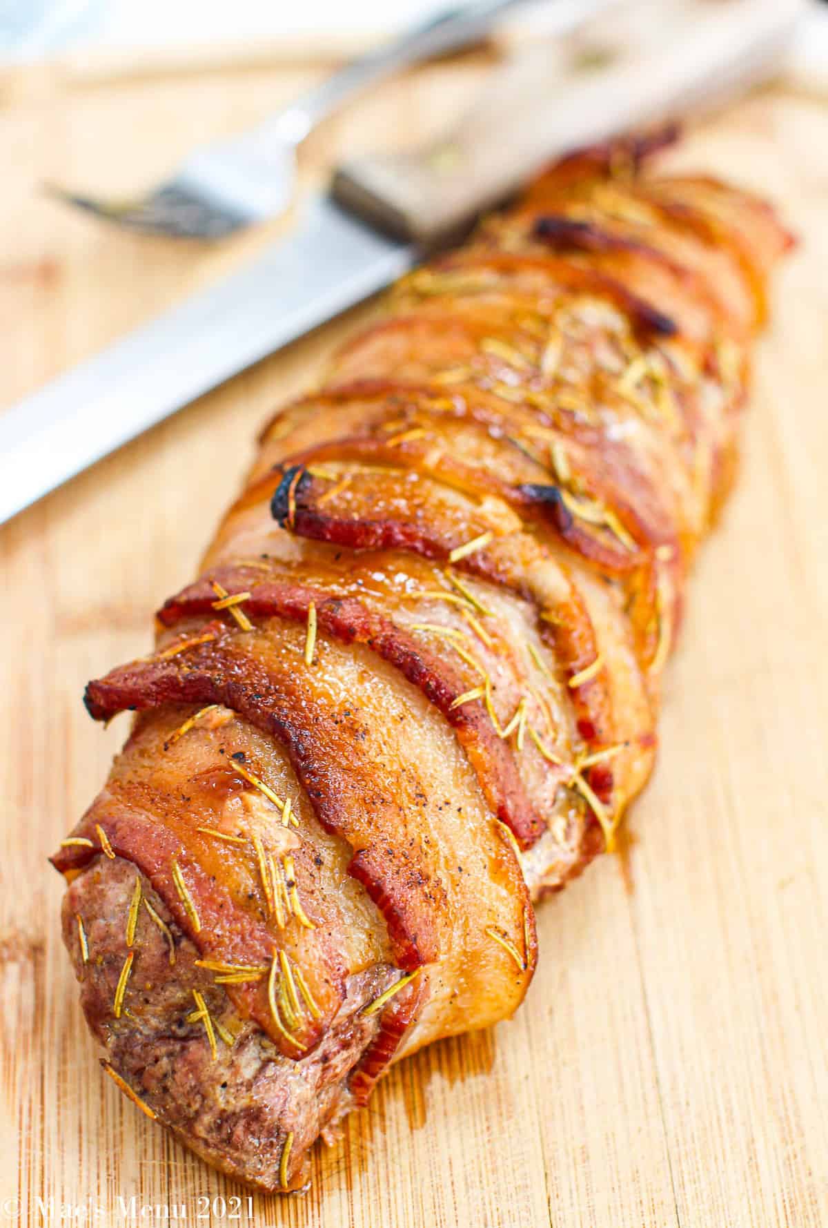 A side shot of maple bacon-wrapped bacon on a wooden cutting board