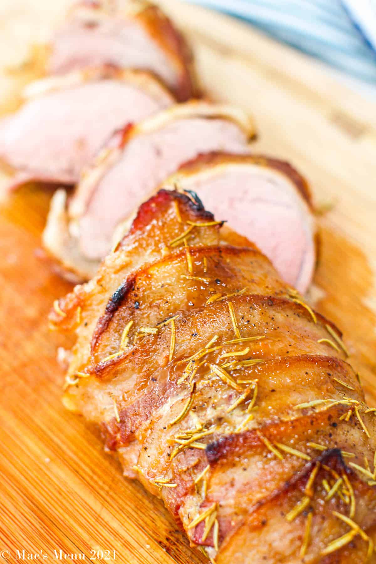A close up shot of sliced bacon wrapped pork tenderloin.