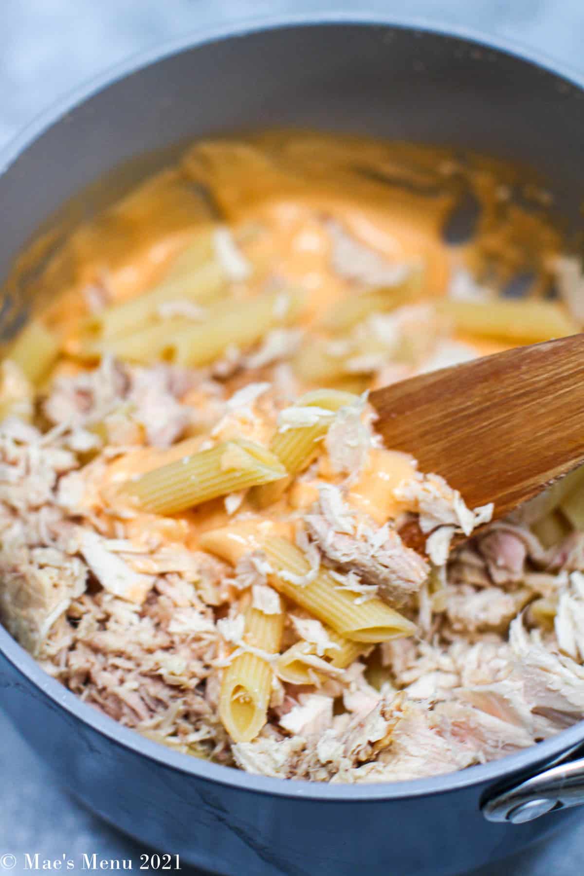 Mixing pasta and flaked tuna into a cheesy sauce
