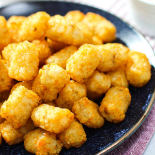 A side angle shot of a plate of air fryer tater tots