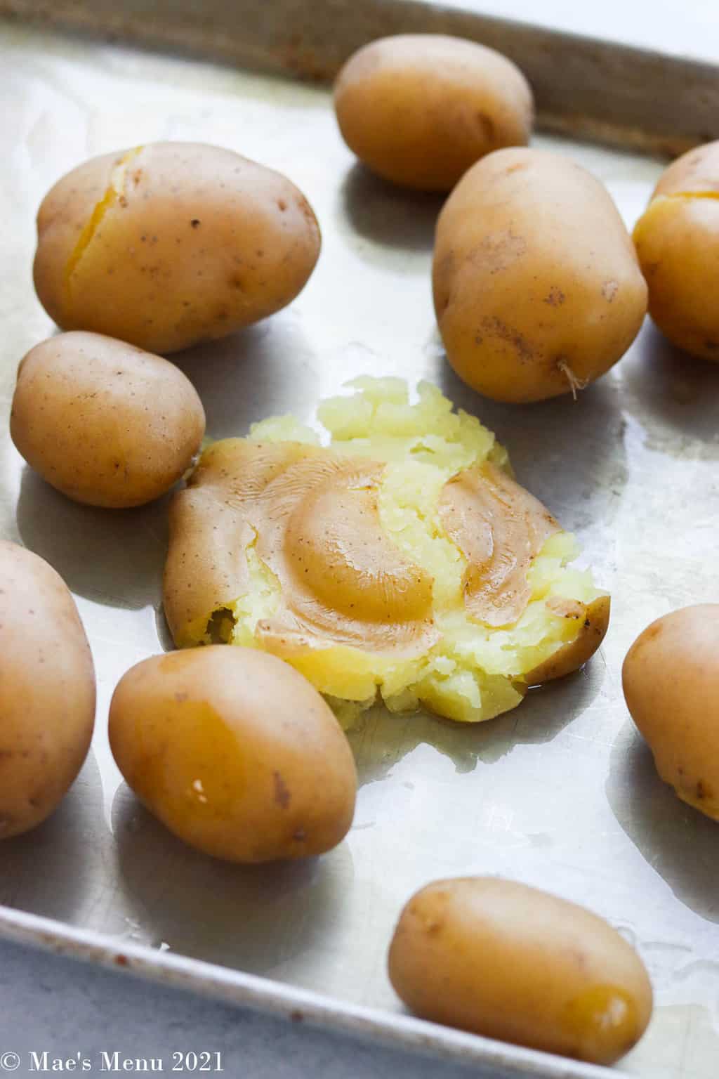 a baking sheet of potatoes with one smashed