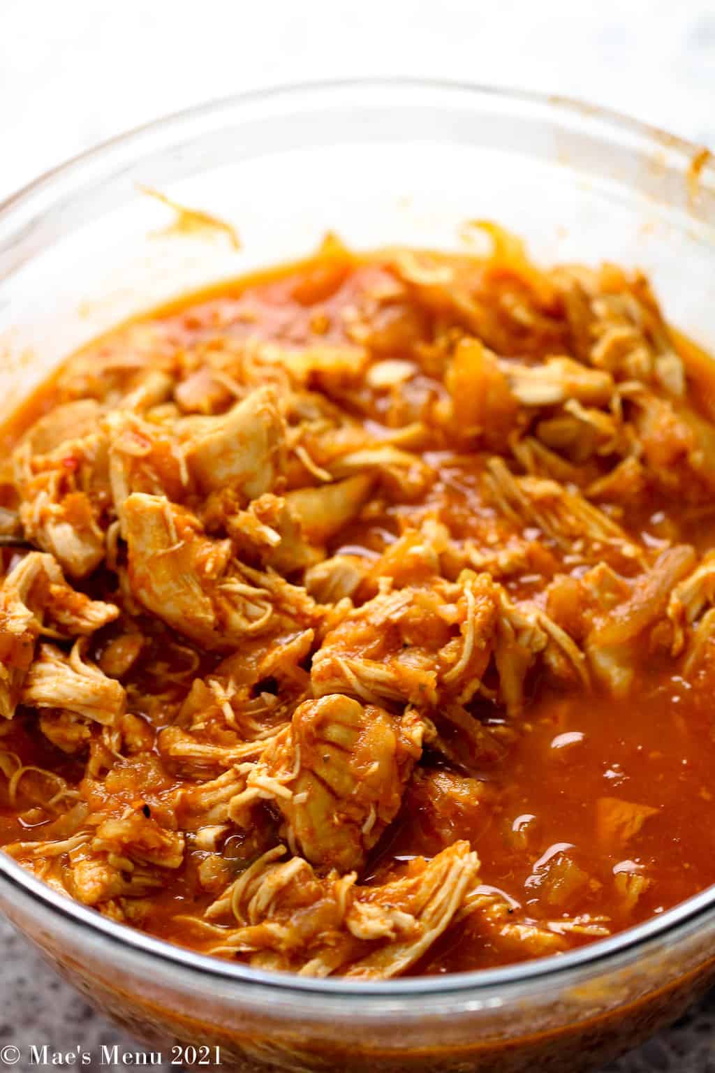 An up-close side shot of the instant pot shredded chicken in a clear mixing bowl