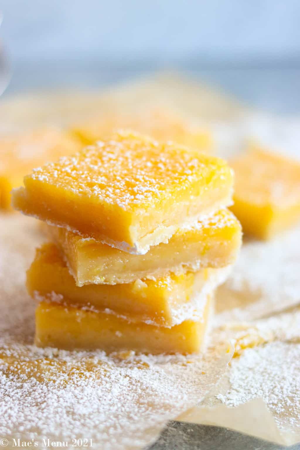 A stack of  lemon bars on parchment paper