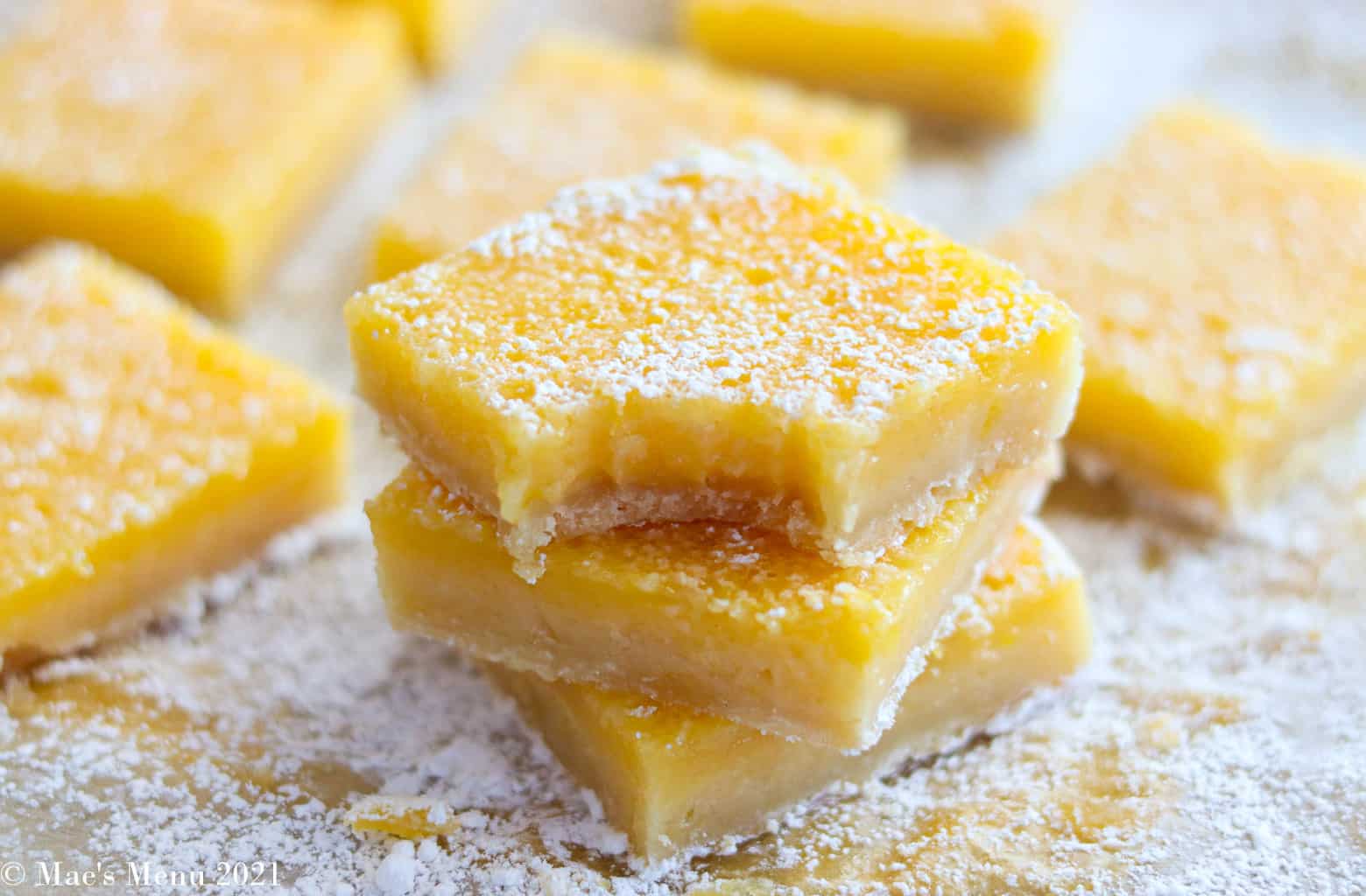 A stack of lemon bars with a bit taken out of one. Lemon bars it eh back