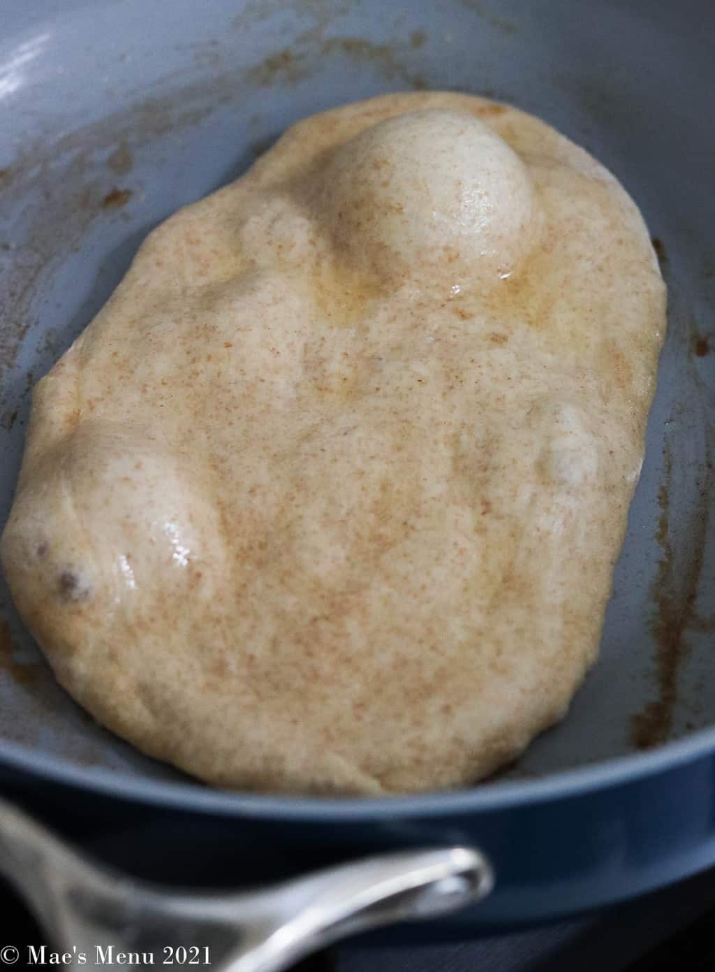 A piece of naan cooking in a skillet