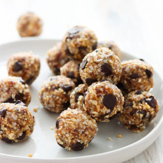 A side angled shot of a white plate of date energy balls