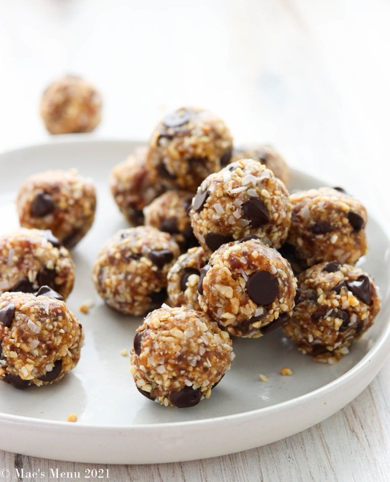 A side angled shot of a white plate of date energy balls