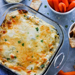 Overhead shot of spinach artichoke dip surrounded by carrots and crackers