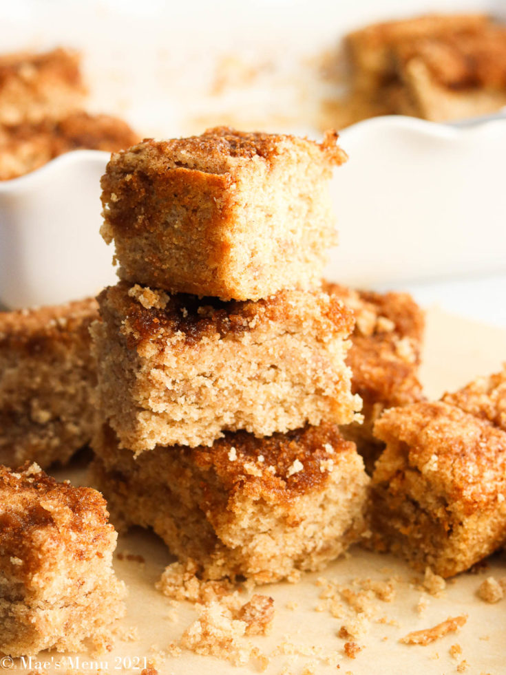 A stack of vegan coffee cake pieces in front of a white pan of the cake