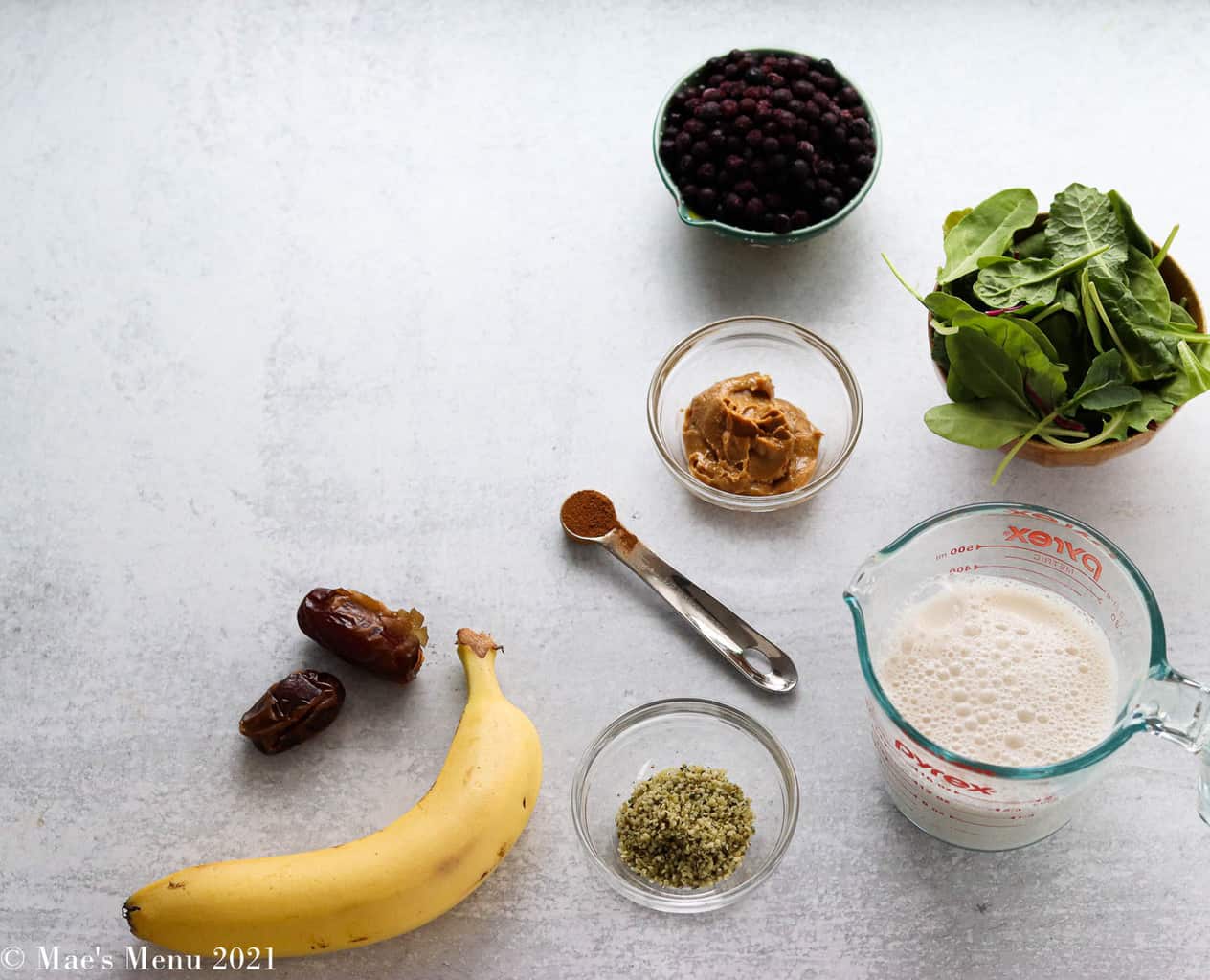All the ingredients for blueberry spinach smoothie on a concrete counter