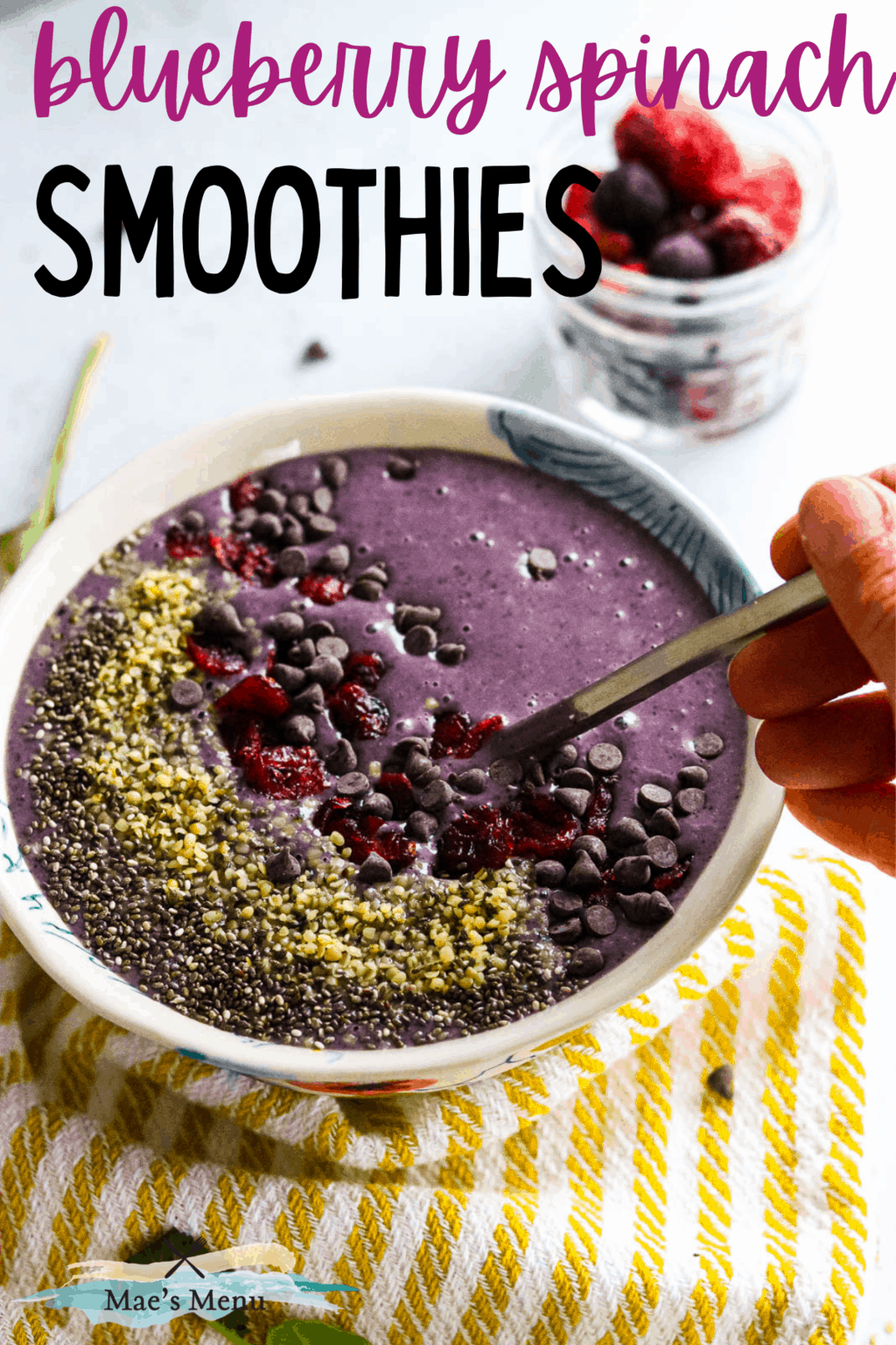 A pinterest pin for blueberry spinach smoothies with a hand scooping into a smoothie bowl of the smoothie