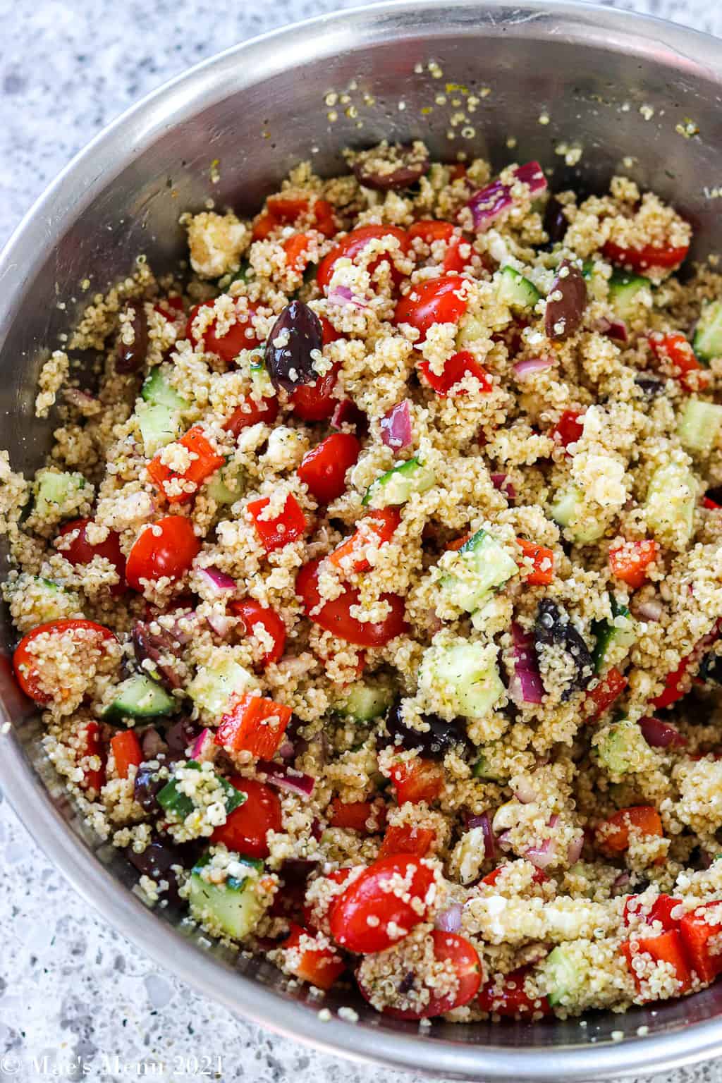An overhead shot of a large mixing bowl of Greek quinoa salad