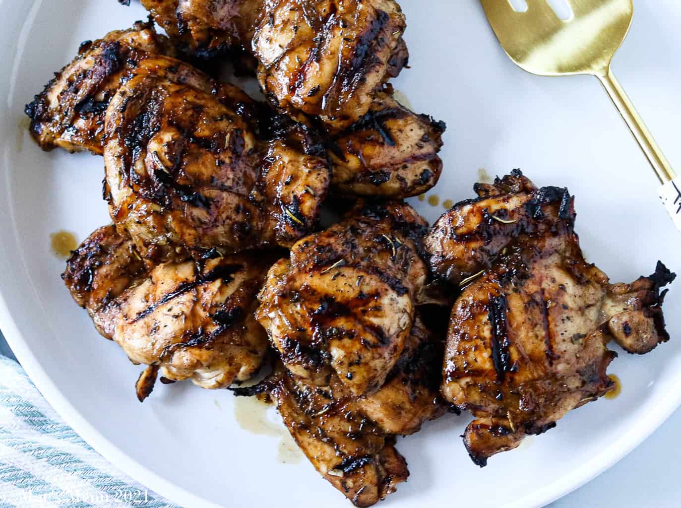 An up-close overhead shot of a white platter of grilled chicken thighs
