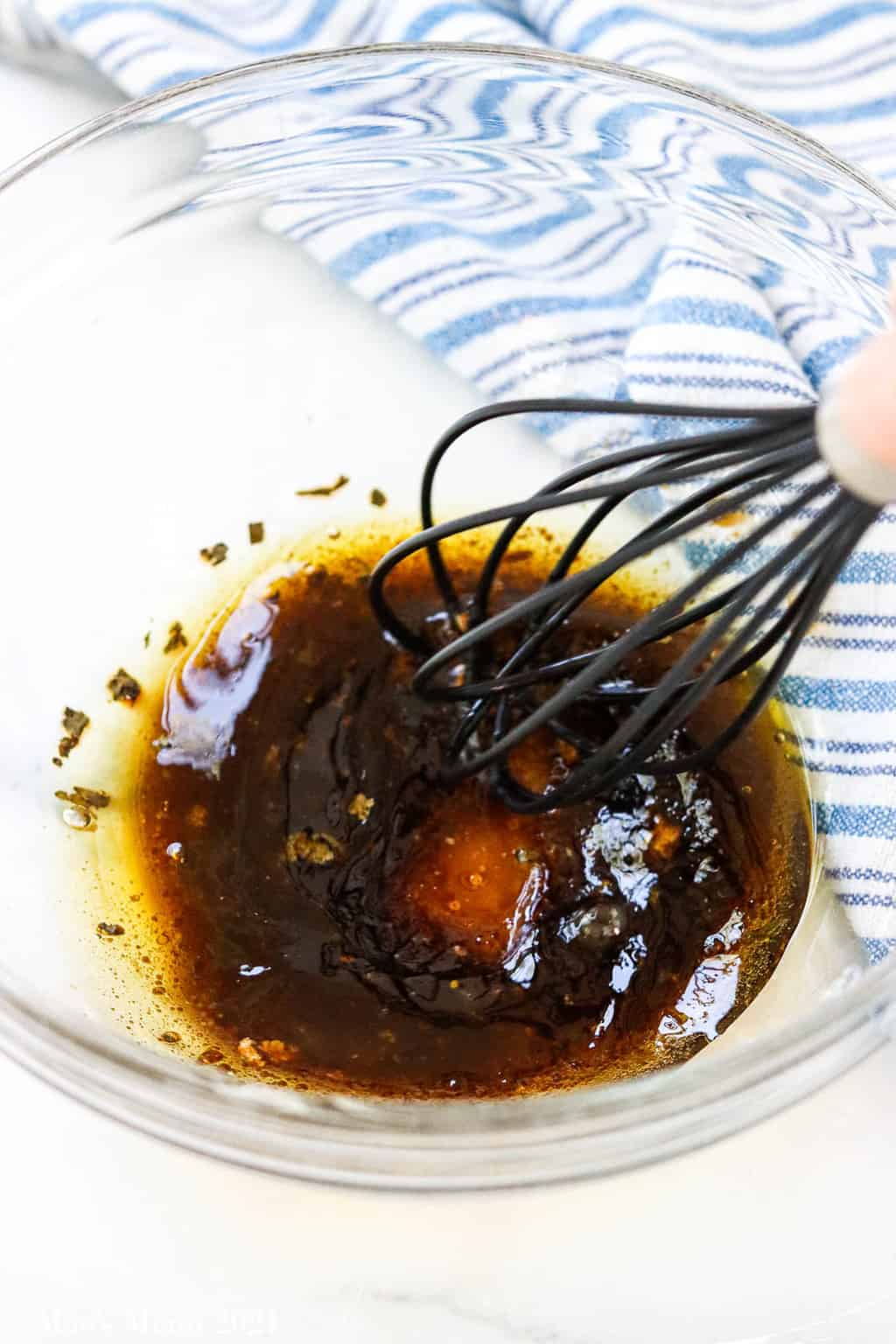 Whisking the balsamic vinaigrette together in a glass mixing bowl