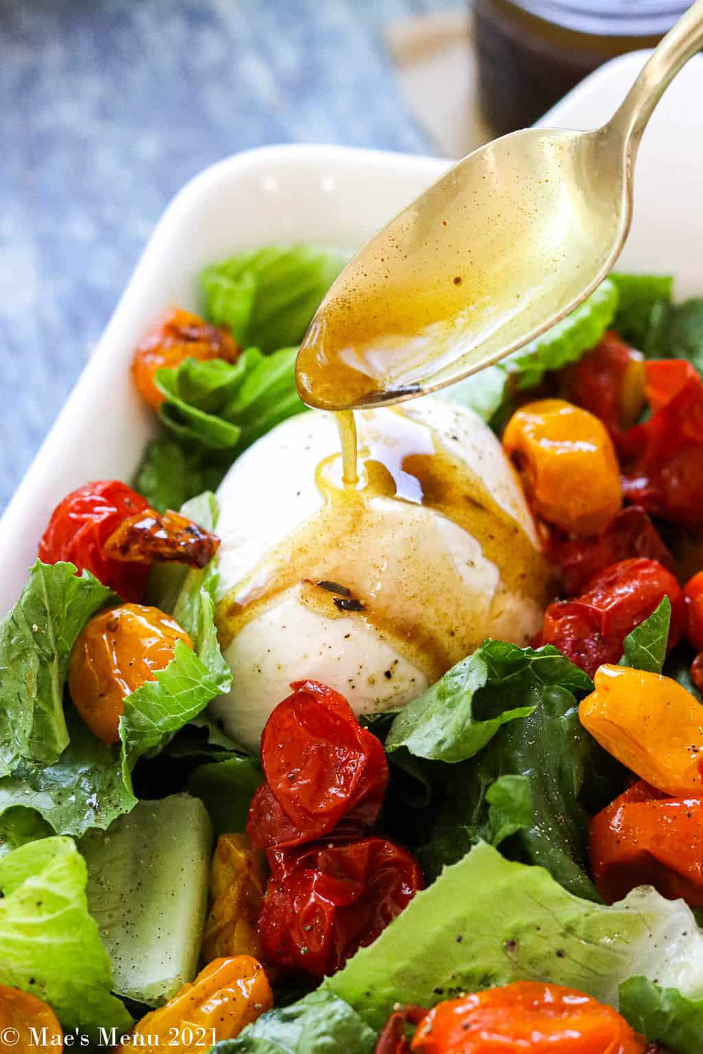 Drizzling the dressing over the burrata salad with roast tomatoes