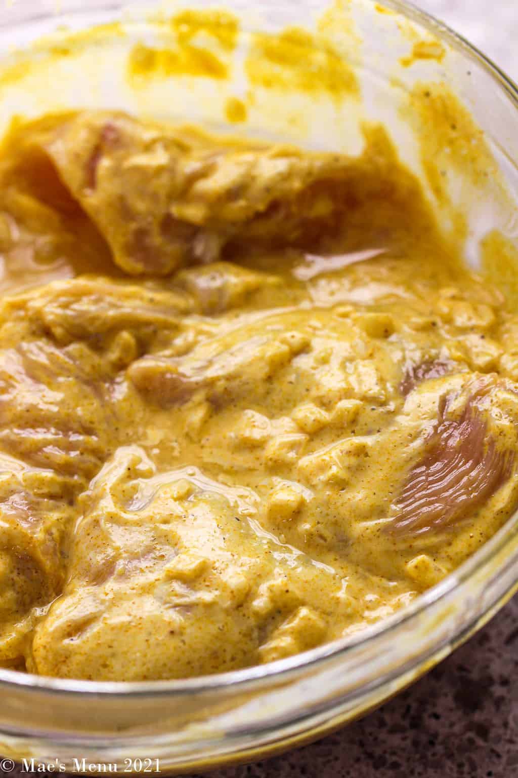 An up-close shot of a bowl of bowl of chicken marinating in yogurt