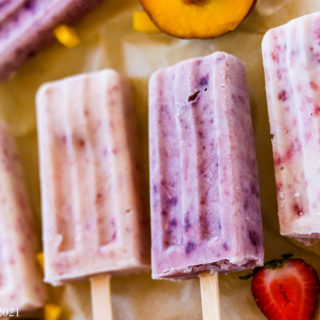 A horizontal shot of 4 yogurt popsicles surrounded by fruit