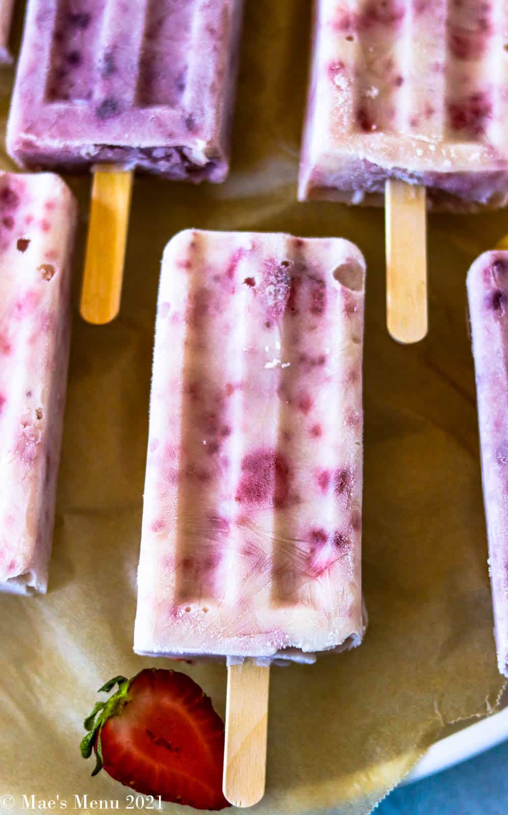 An up-close overhead shot of popsicles on a sheet of parchment paper