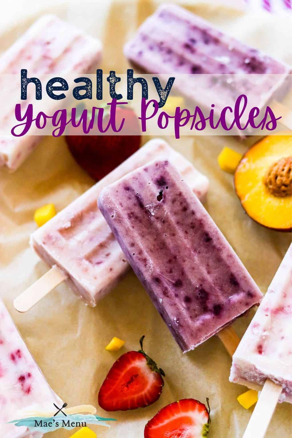 A pinterest pin for healthy yogurt popsicles with an up-close photo of the popsicles on a piece of parchment with fruit