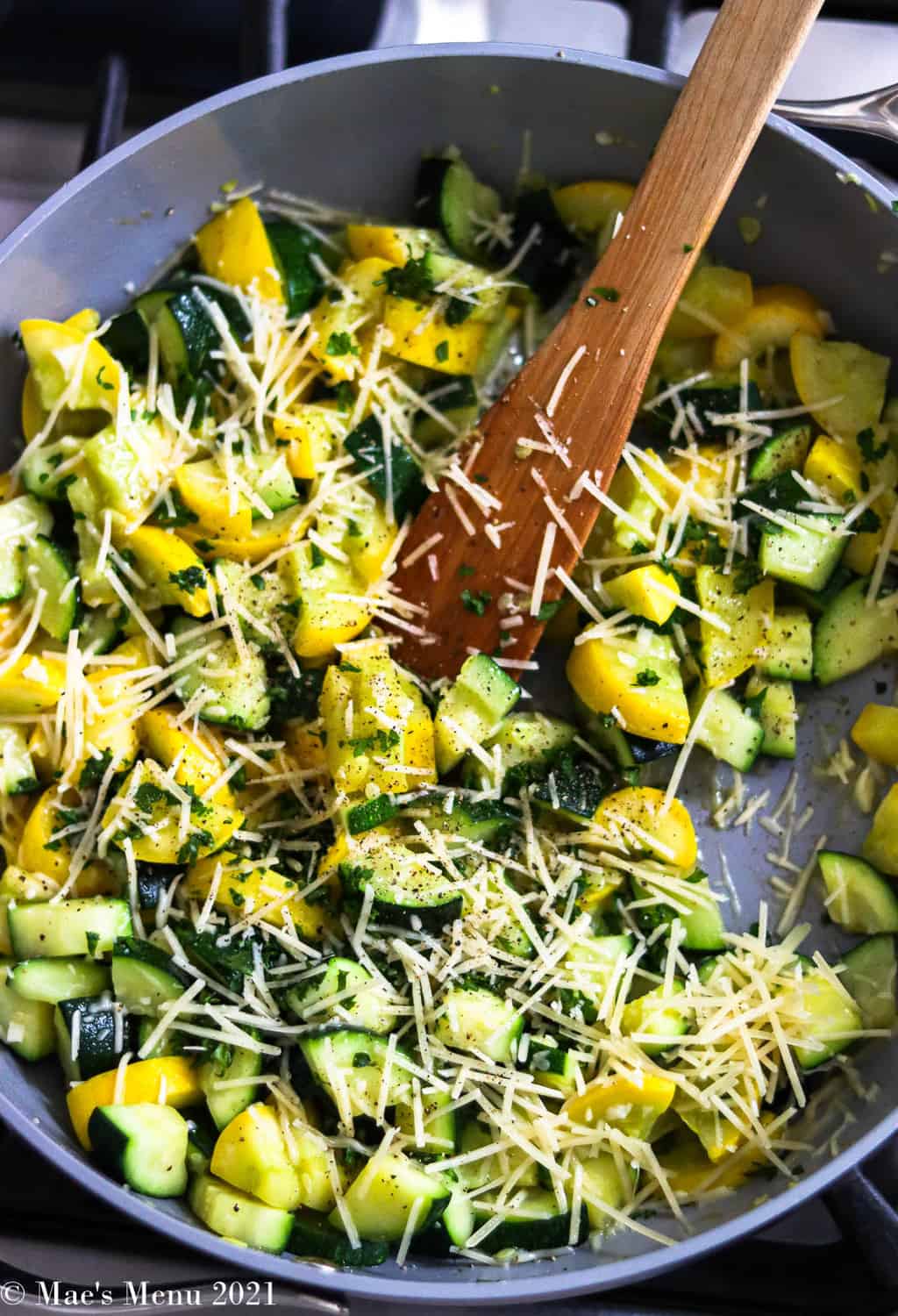 An overhead shot of a pan of yellow squash and zucchini with parmesan cheese and parsley