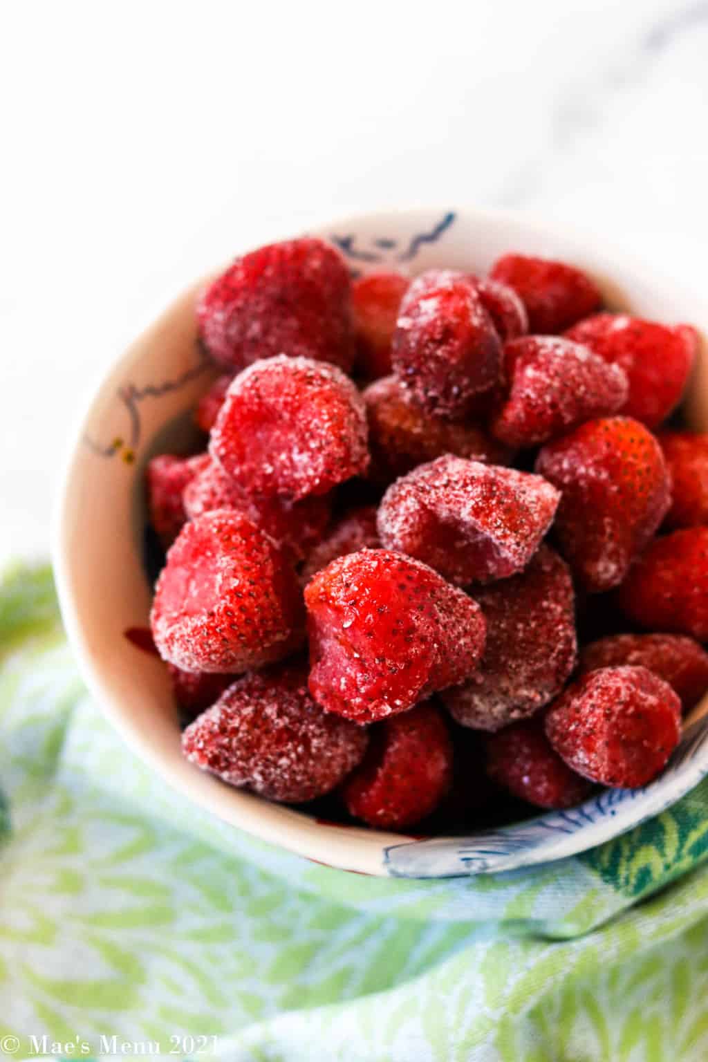 A side shot of a bowl of frozen strawberries