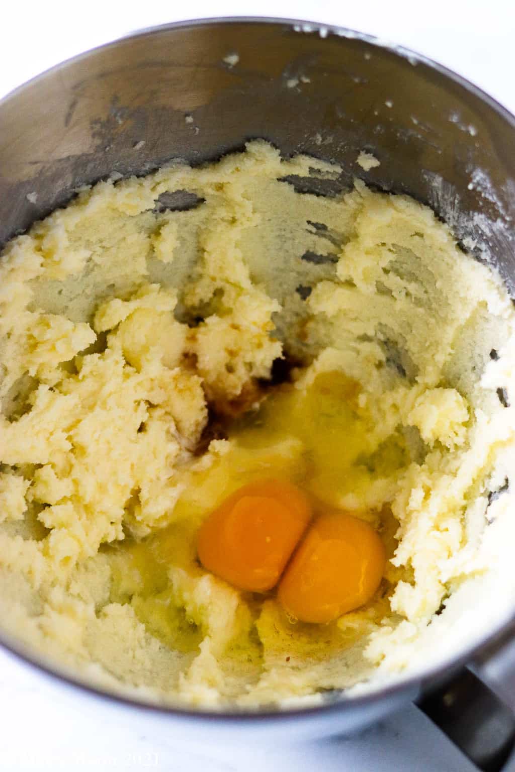 A mixing bowl of creamed butter and sugar and two large eggs